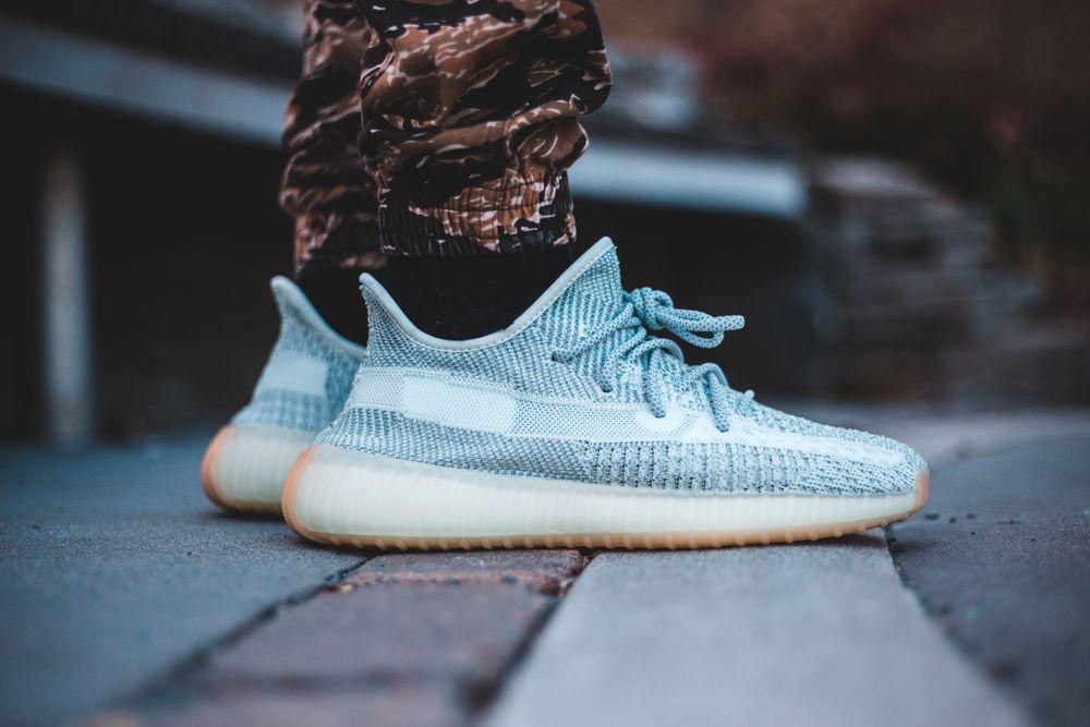 A close-up of pale blue sneakers worn on a city pavement